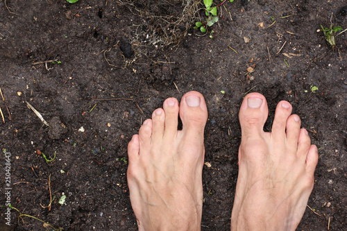 Fotografía barefoot man stands on empty black soil ground in spring, poster for ecology fit
