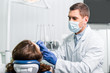 © LIGHTFIELD STUDIOS - dentist in mask working with woman in latex gloves in dental clinic