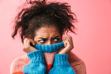 Wall Mural - Displeased beautiful young african woman posing isolated over pink wall background covering face with sweater.