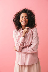 Wall Mural - Happy beautiful young african woman posing isolated over pink wall background.