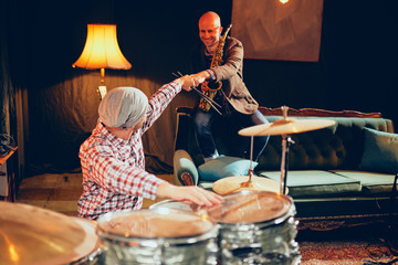 Canvas Print - Musicians giving fist bump. On picture saxophonist and drummer sitting in home studio.