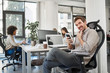 © nenadaksic - CEO with smile sitting in his chair and using smart phone. Office interior, in background employees working.