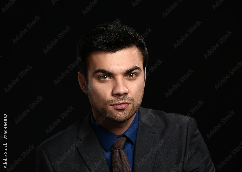 Portrait of handsome young businessman on dark background