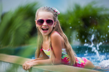 cute cheerful smiling girl in sunglasses in the pool on holiday. summer time
