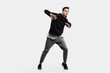 © Leika production - Stylish young man wearing a black sweatshirt and gray pants is dancing street dances on a white background