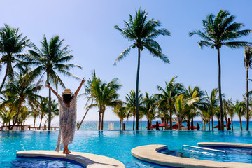 woman by swimming pool in tropical resort