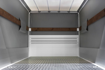 Empty cargo truck, van inside, fragment of commercial transport, vehicle detail with steel floor and gray tarpaulin walls, delivery service concept 