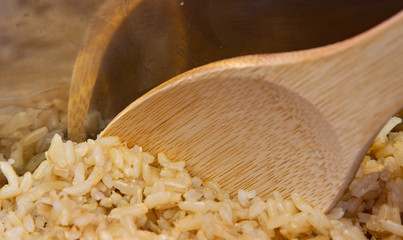 Wall Mural - Cooked brown rice in a pot with a wooden spoon