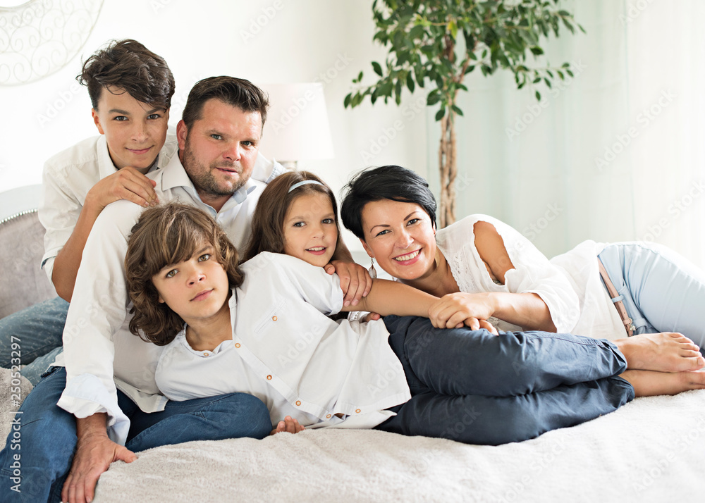  happy family with two children lying down and looking at camera - portrait  - obrazy, fototapety, plakaty 