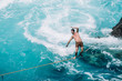 © Cavan Images - Carefree young man slacklining on rope over sea during sunny day