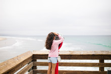 Rear View Of Girl Looking Through Coin-operated Binoculars While Standing By Sea Against Cloudy Sky