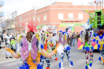 Unrecognizable group of costumed beauty design participants enjoy outdoors street show annual carnival event. Positive energy and popular recreation activities on flowers and feathers decor background