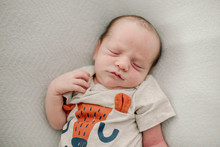 Overhead View Of Cute Newborn Baby Boy Sleeping On Bed At Home