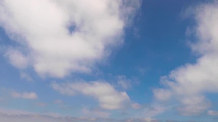 Wall Mural - looping one minute footage features white puffy clouds on a sunny day moving across a deep blue sky.