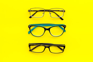 Wall Mural - Set of glasses with transparent lenses on yellow background top view