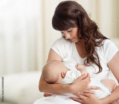 Cuadros en Lienzo Young mother feeding breast her baby at home in white room