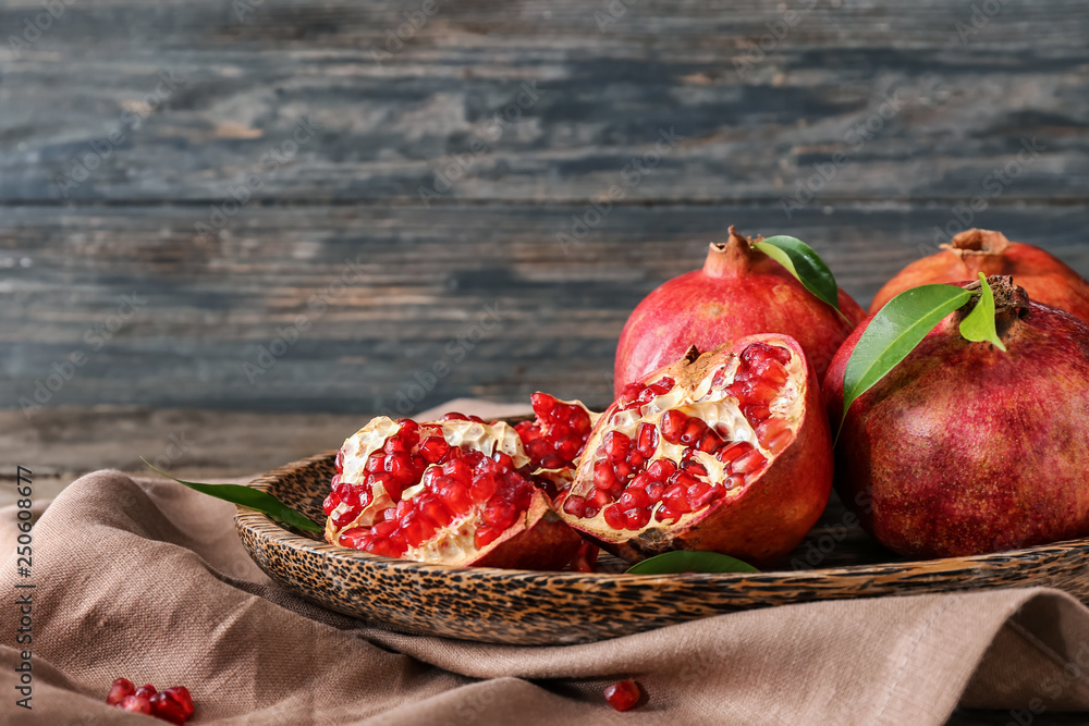 Plate with ripe pomegranates on table