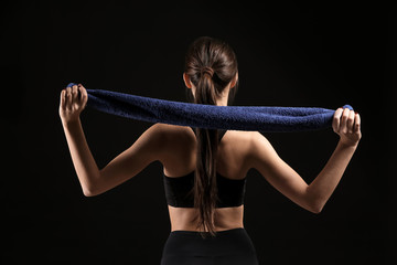 Wall Mural - Sporty young woman with towel on dark background