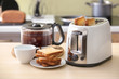 © Pixel-Shot - Toaster with bread slices and carafe of hot coffee on table