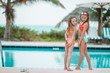 © travnikovstudio - Adorable little girls having fun in outdoor swimming pool on summer vacation