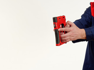 man in overalls holds tool stapler on white background.