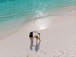 Beautiful beach with white sand and clear blue sea. Couple on the beach