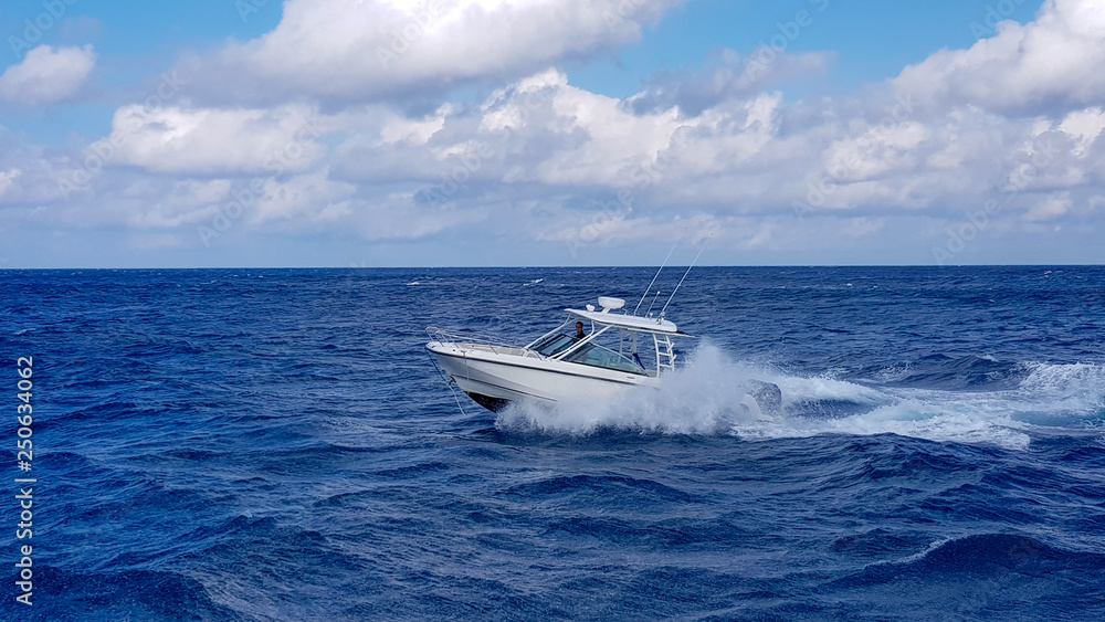 Speed fishing tender boat jumping the waves in the sea and cruising the blue ocean day in Bahamas. Blue beautiful water - obrazy, fototapety, plakaty 