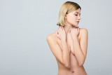 beautiful naked tender girl covering breast, isolated on grey