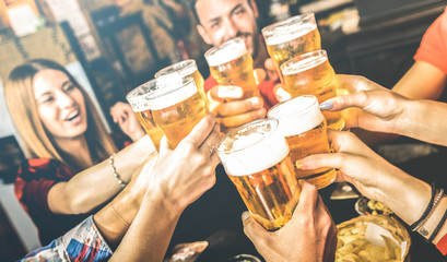 Friends drinking beer at brewery bar restaurant on weekend - Friendship concept with young people having fun together toasting brew pint on happy hour at pub - Focus on glass - Bright contrast filter