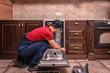 © Ахтем - Young Male Technician Repairing Dishwasher In Kitchen