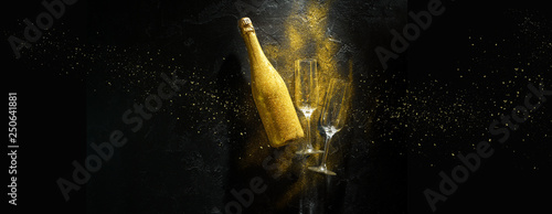 Cuadros en Lienzo Romantic image of golden champagne bottle, two wine glasses on black stone backg