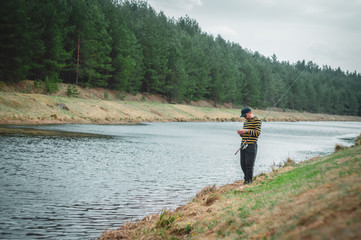 Fisherman with rod on the river bank.