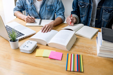 Wall Mural - high school tutor or college student group sitting at desk in library studying and reading, doing ho