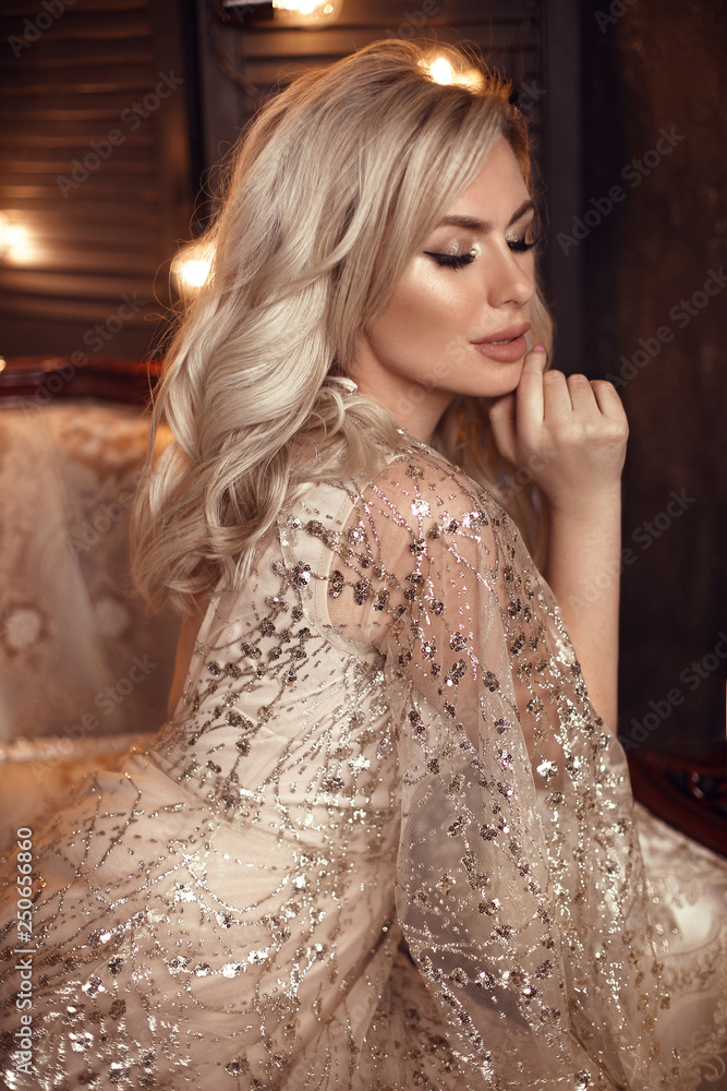 Photo Stock Elegant blond woman in beige dress posing on luxury sofa in royal interior. Fashion beautiful sensual bride with makeup, curly hair style in luxurious prom gown. | Adobe Stock Photo Stock Elegant blond woman in beige dress posing on luxury sofa in royal interior. Fashion beautiful sensual bride with makeup, curly hair style in luxurious prom gown. | Adobe Stock