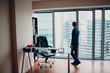 © primipil - A man in a skyscraper office is standing by a panoramic window.