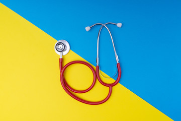 Wall Mural - Stethoscope on blue and yellow background with selective focus