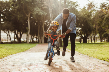 father teaching his son cycling at park