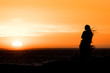 © laura - Sunset silhouette: same sex couple of girls at sunset in Camps Bay Tidal Pool, Cape Town, South Africa