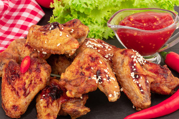 Wall Mural - Baked chicken wings with sesame seeds and sweet chili sauce on dark background