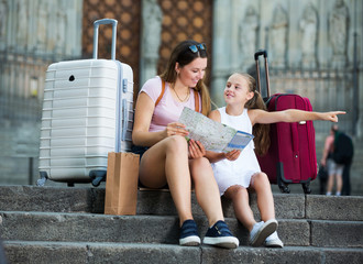 Wall Mural - mother and daughter travelers sitting on stone stairs