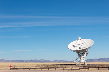 Wall Mural - very large array detail of radio antenna against a blue sky and distant mountains, listening to spac