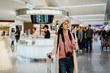 © PR Image Factory - information desk in International Airport. female passenger in hat holding cellphone finding direction of departure gate terminal. young girl foreigner standing in lobby looking up road sign.