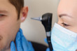 © Med Photo Studio - close up photo of a female otolaryngologist examining the ear of a male patient