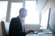 © Med Photo Studio - lateral view of a young man working on the computer in a light gray room