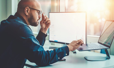 Professional male currency trader making research in financial market working on laptop computer in office, millennial businessman analyst studying infographics data for report. Banking blockchain