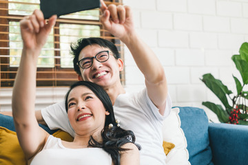 Wall Mural - Young Asian couple lover taking selfie by mobile phone at home, relax and lifestyle at home concept