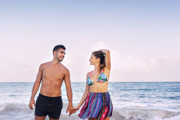 Young couple holding their hands at the beach