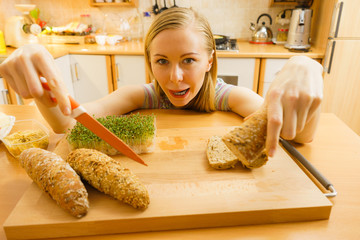 Woman in kitchen holding knife making healthy sandwich