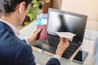 © Artem - Man businessman holding airline ticket and passport buying on the Internet using a laptop. Purchasing and booking online