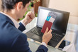 © Artem - Man businessman holding airline ticket and passport buying on the Internet using a laptop. Purchasing and booking online